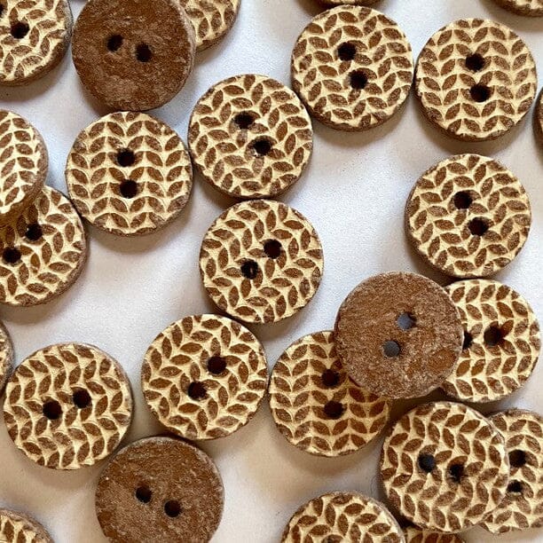 Wooden buttons with knitted pattern on a white background