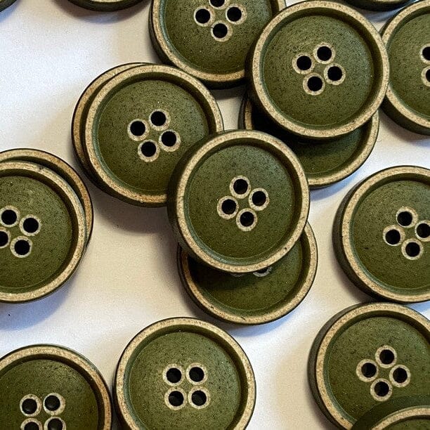 Collection of green buttons with brown edges on a white background