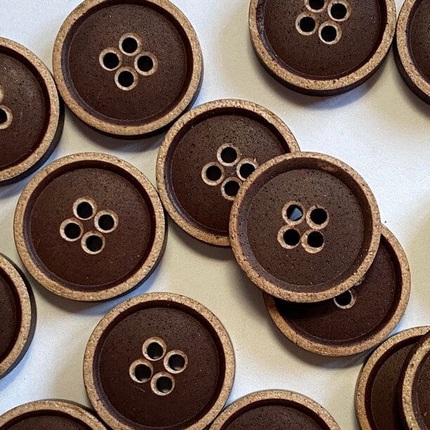 Pattern of brown buttons with four-hole design on a light background