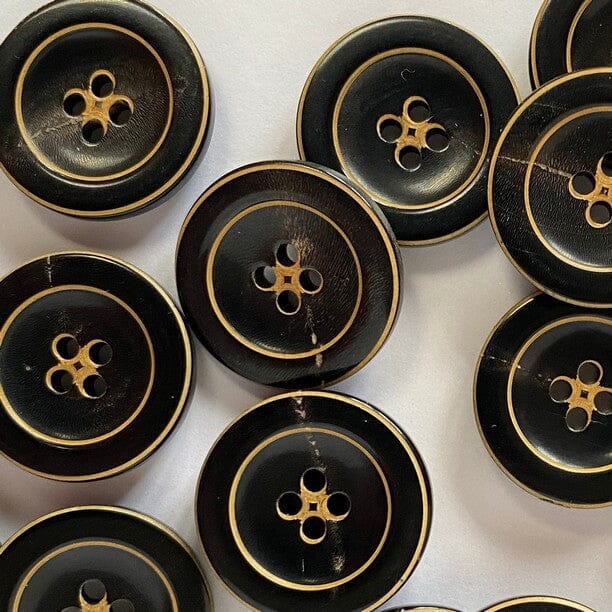 Black buttons with gold detailing arranged on a white background