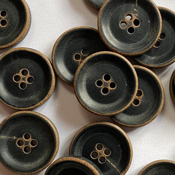 Collection of matt black buttons with four holes on a white background