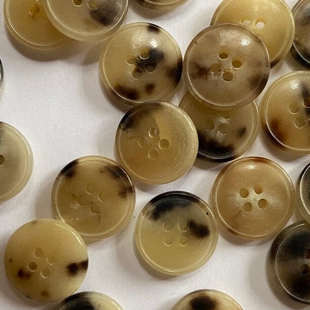 Collection of brown buttons with black spots on a white background