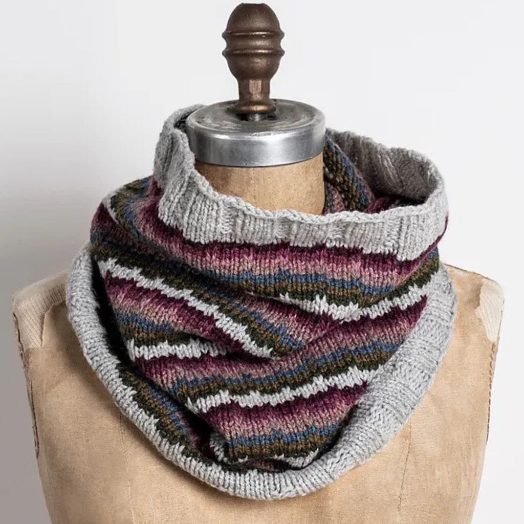Knitted cowl with multicolor pattern on a mannequin against a neutral background