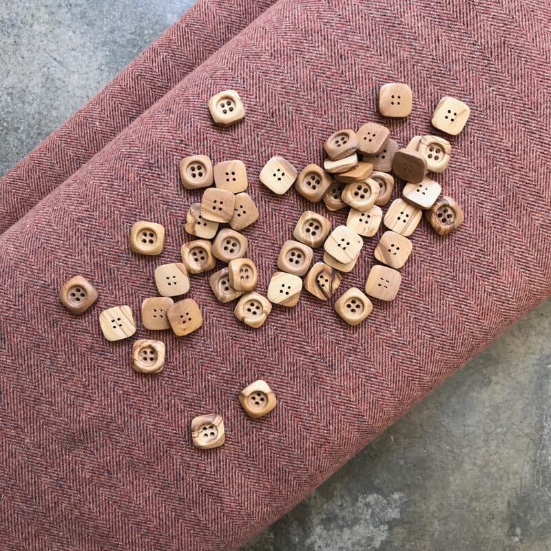 Wooden buttons scattered on a textured pink fabric background