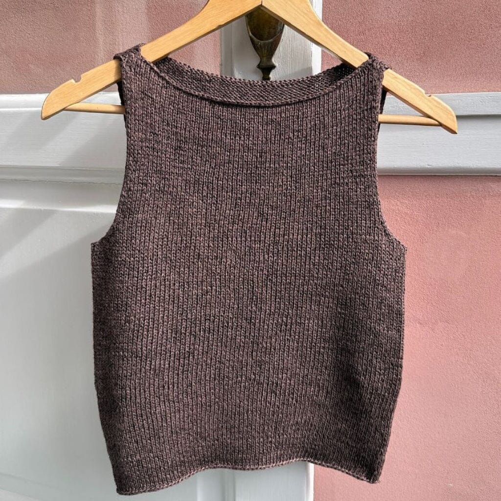 Brown knitted tank top on a wooden hanger against a pink wall.