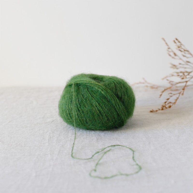 Green skein of yarn on a white fabric background