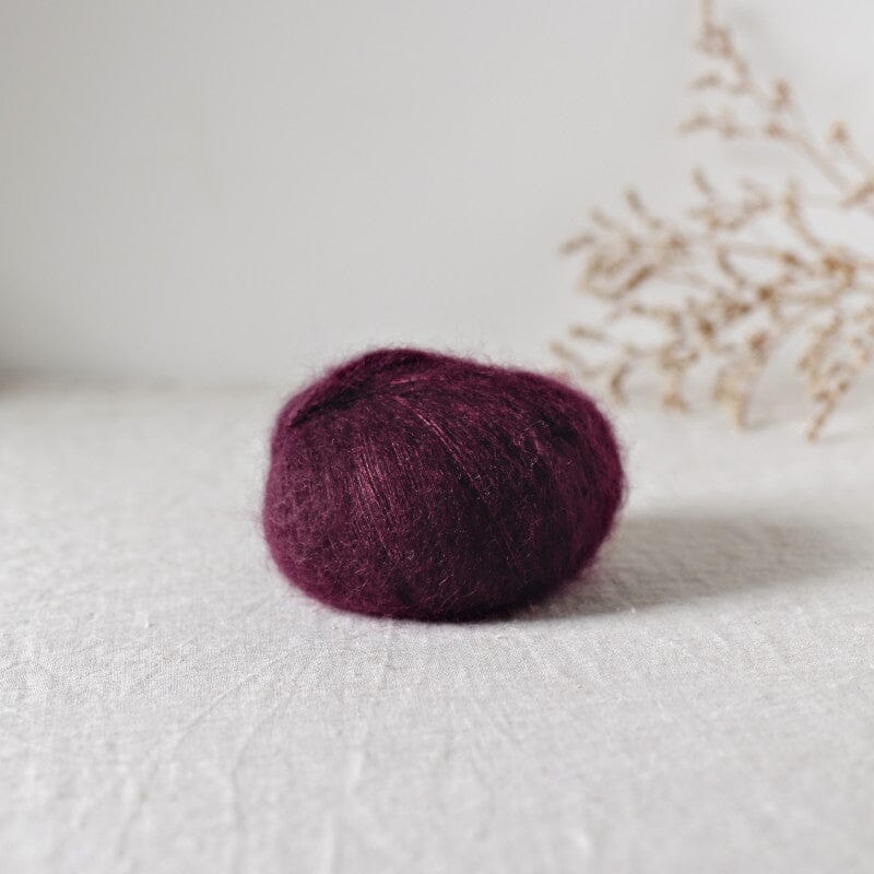 Purple mohair ball on a light surface with a blurred natural background