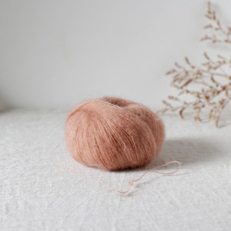 Ball of pink mohair on a textured surface with a light background