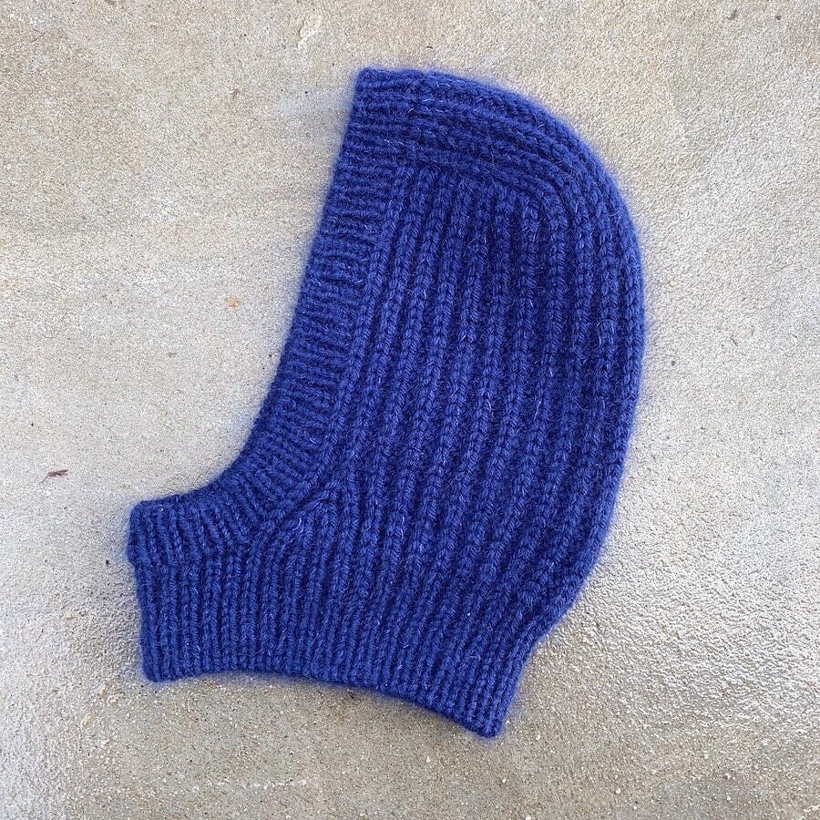 A single blue ribbed knit hood on a textured concrete surface.