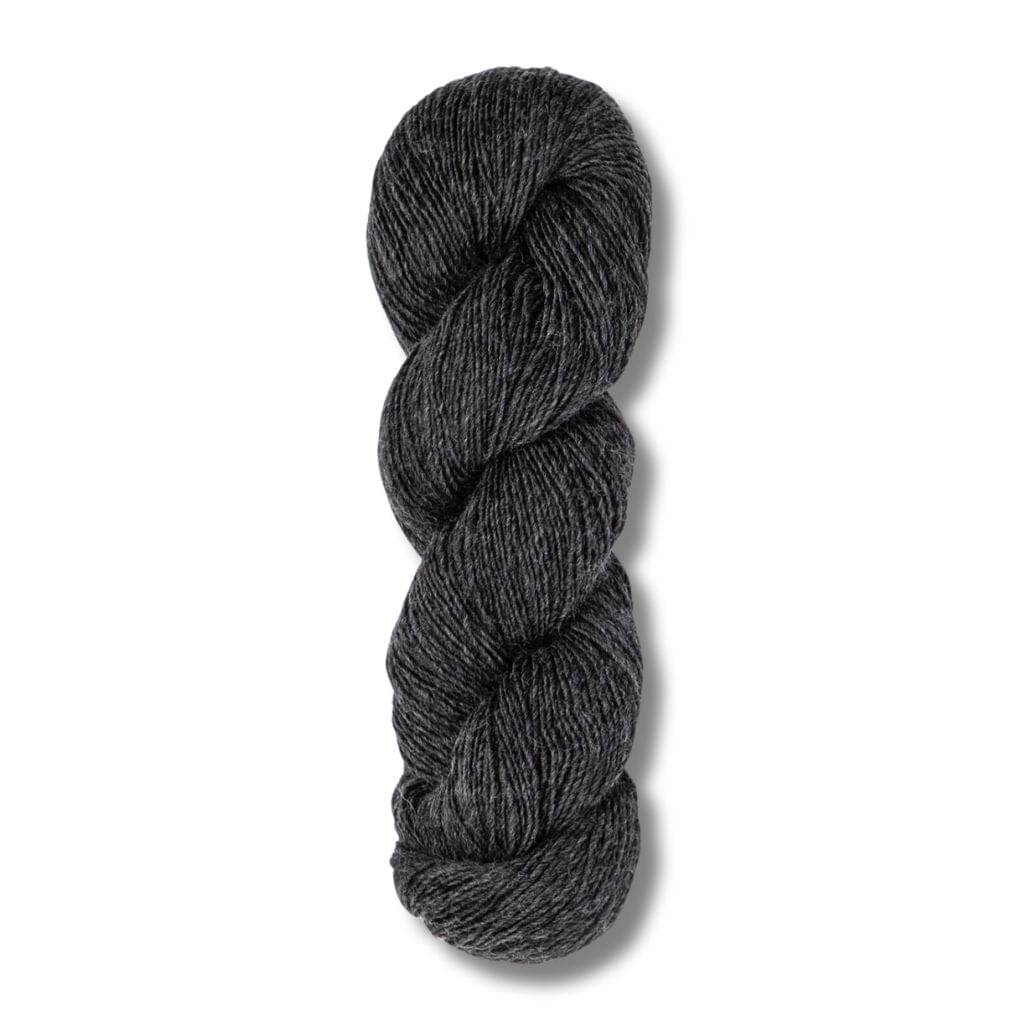 Several skeins of Blue Sky Fibers Woolstok Light yarn in various colors including yellow, green, blue, and black, displayed on a wooden surface.