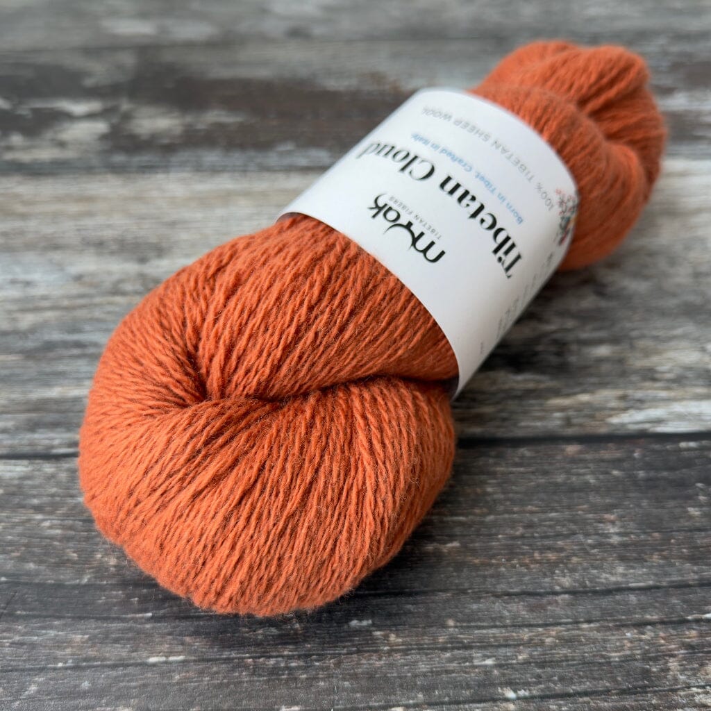 Orange skein of yarn with a label on a wooden surface