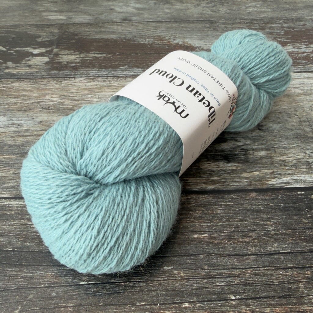 Teal skein of yarn with a label on a wooden surface
