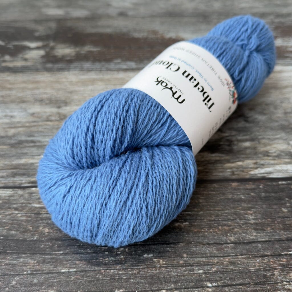Blue skein of yarn with a label on a wooden surface