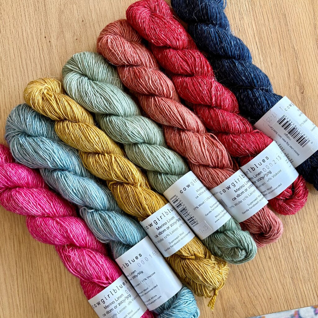 7 skeins of yarn in various colours on wooden table
