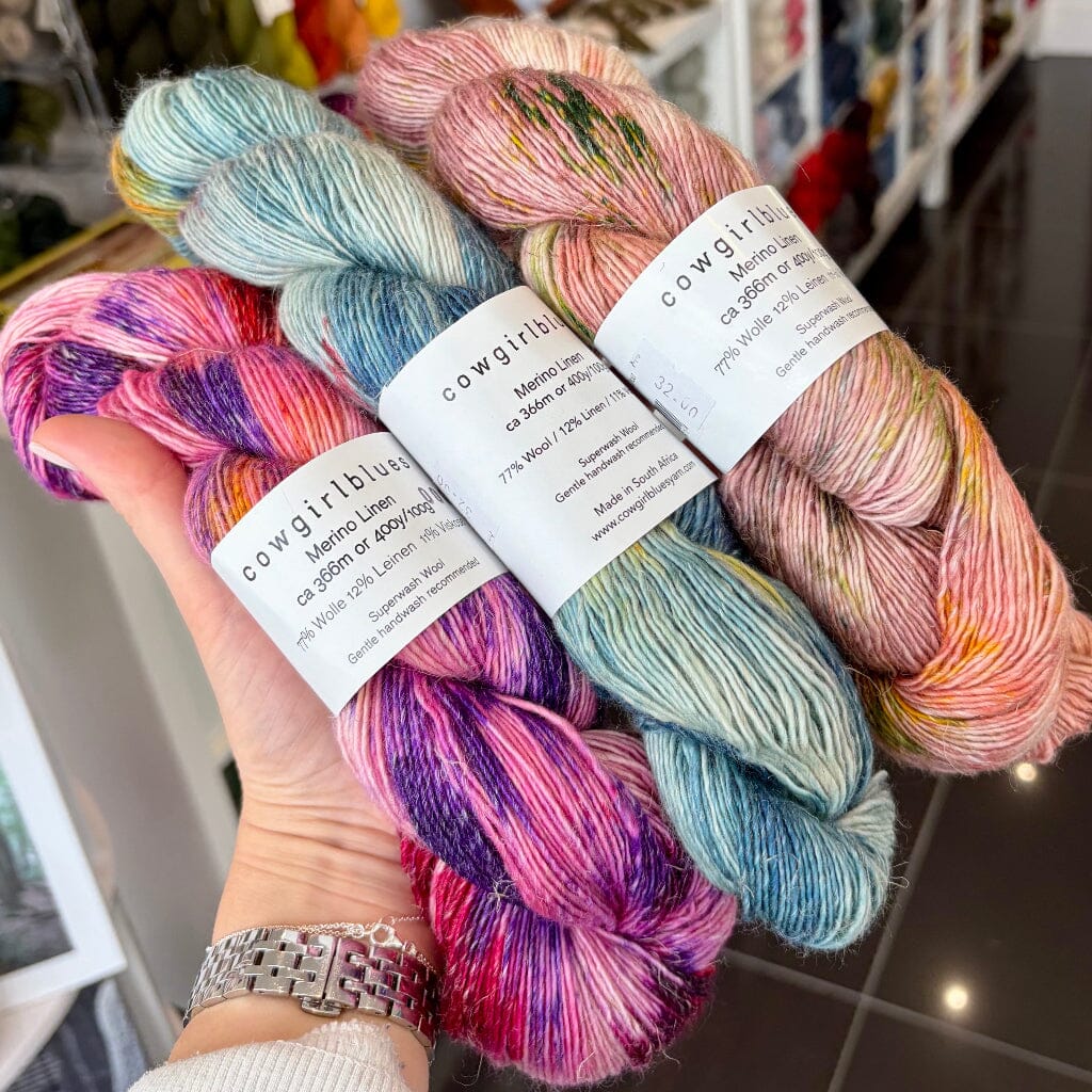 3 multi coloured skeins of merino linen yarn in someones hand