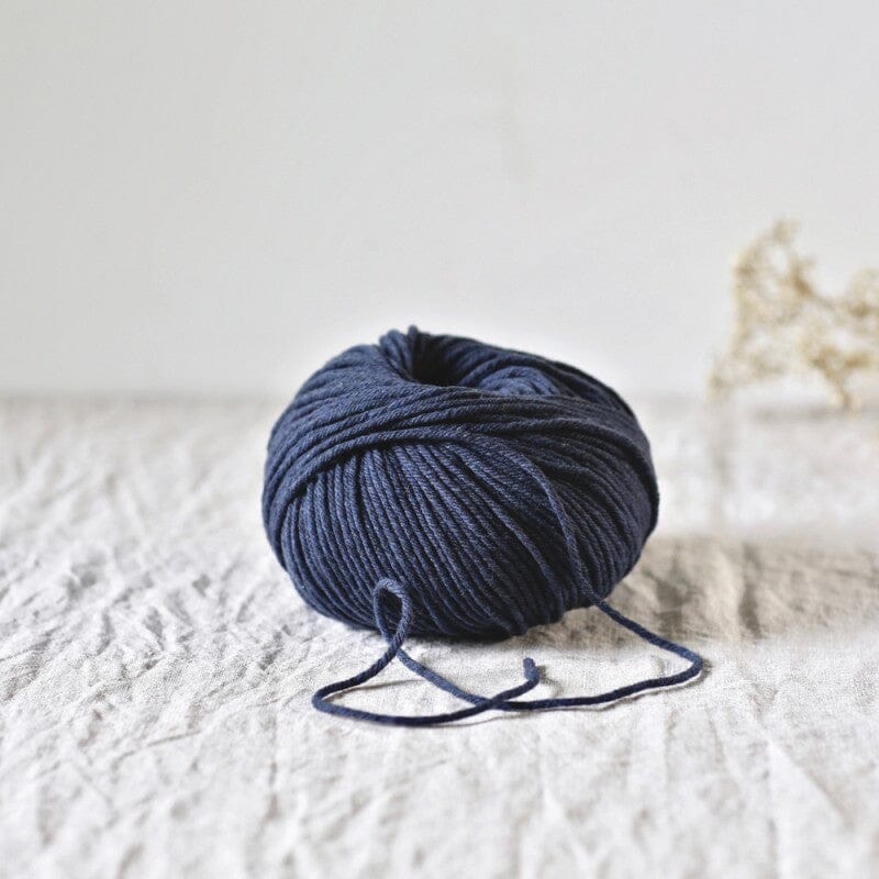 navy  skein of yarn on a textured white surface