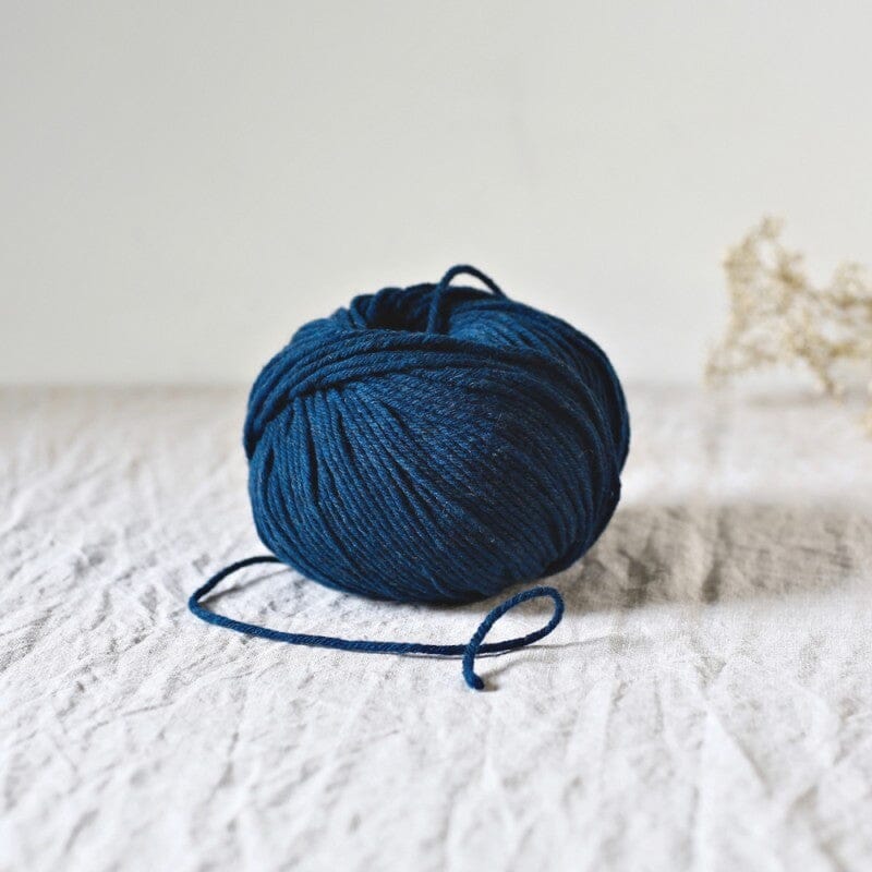 Blue skein of yarn on a textured white surface