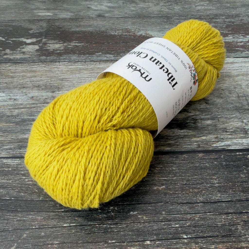 Yellow skein of yarn with a label on a wooden surface