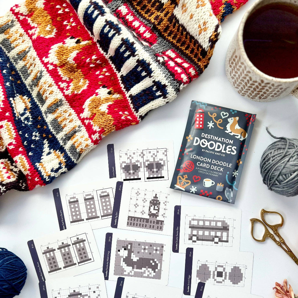 Knitted items, card deck, and yarn on a white surface