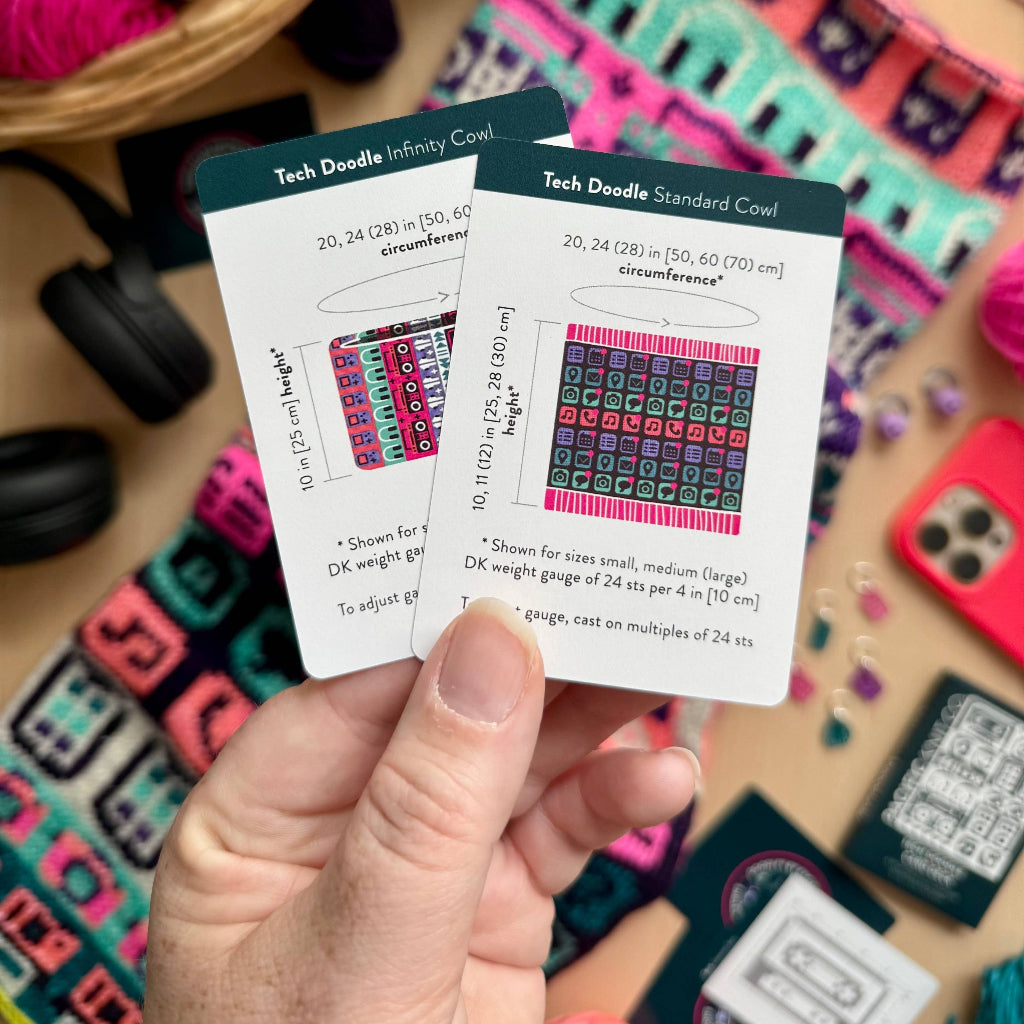 A hand holds two knitting card templates from Tech Doodle, showing the 'Infinity Cove' and 'Standard Cove' patterns. The background is a cozy, colorful craft table filled with yarn skeins, knitting needles, and finished knitted pieces.