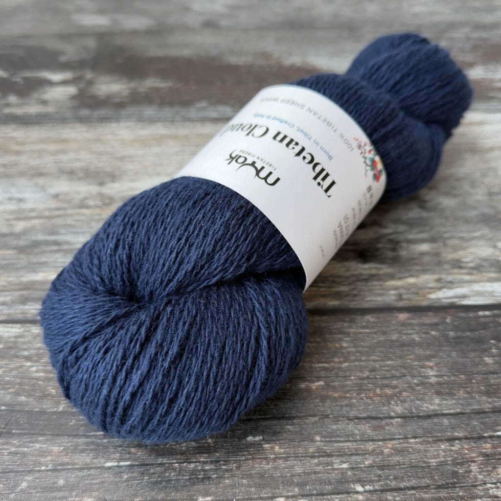 Navy blue skein of yarn with a label on a wooden surface