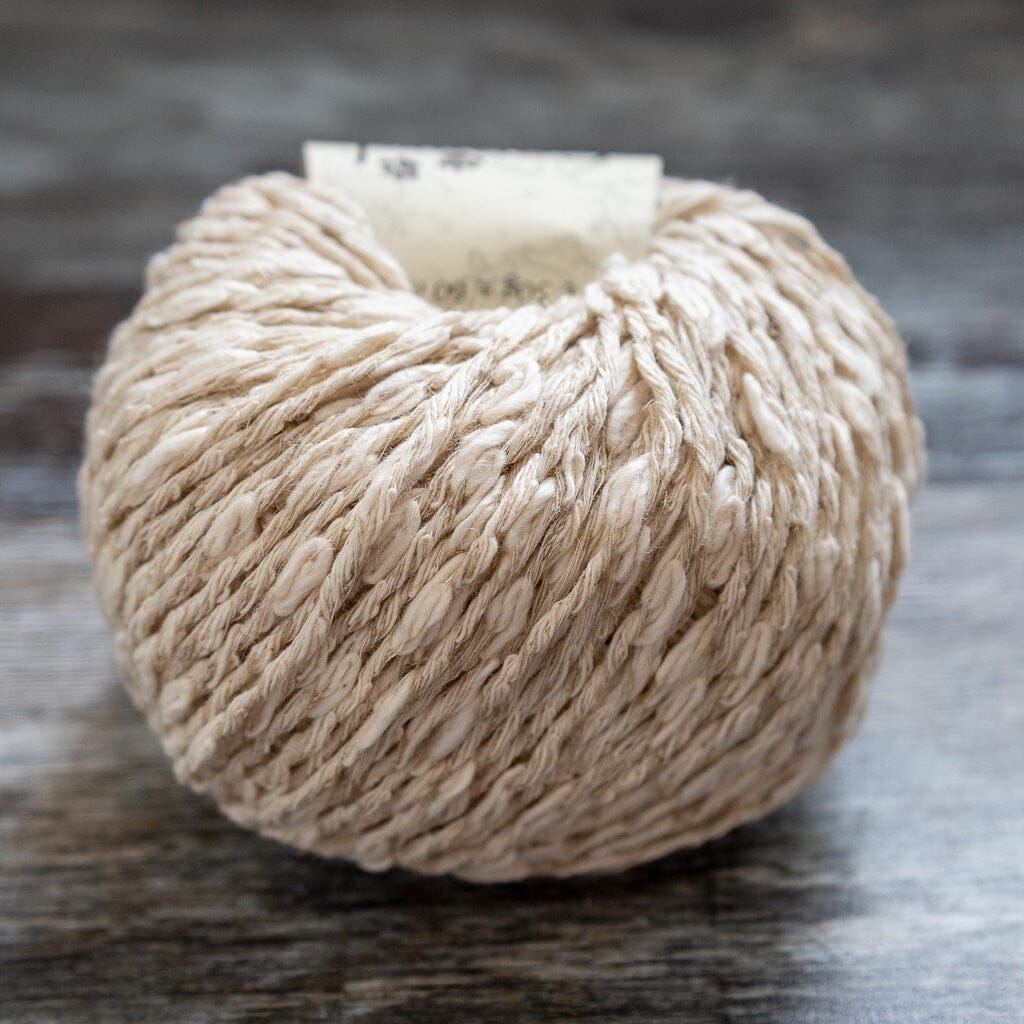 Ball of beige yarn on a textured surface