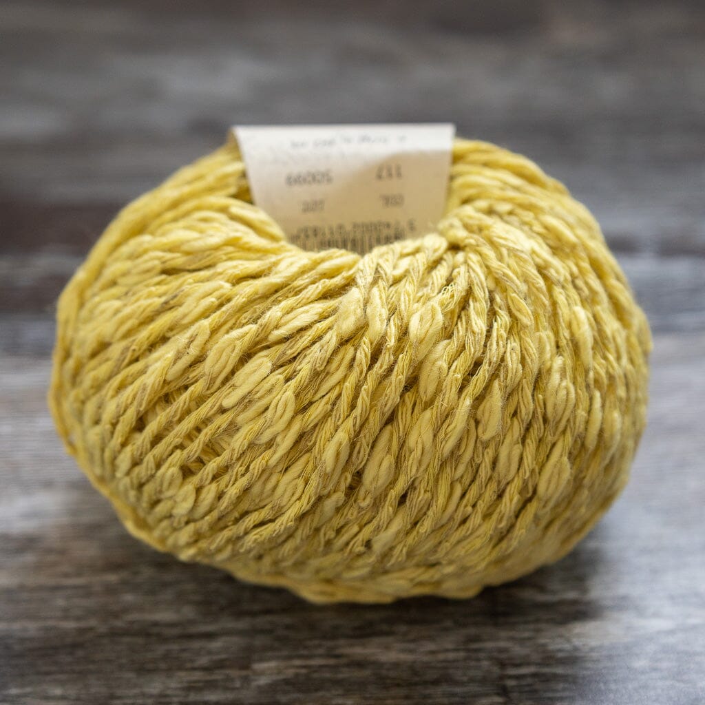 Yellow yarn ball with a label on a gray surface