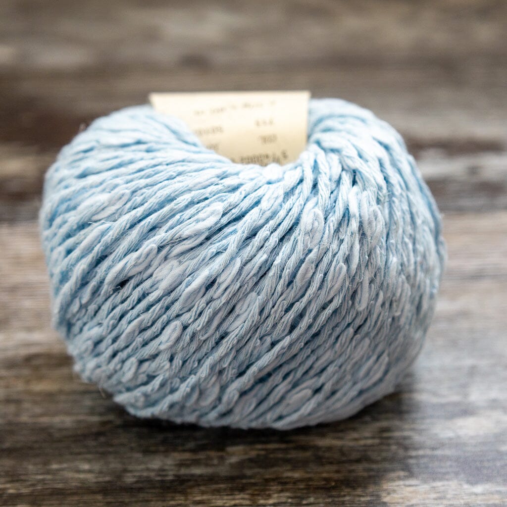 Ball of light blue yarn on a wooden surface