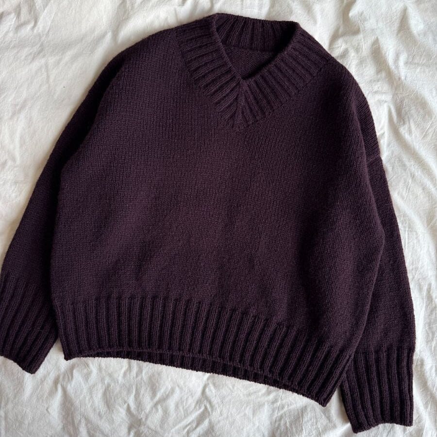 Purple sweater on a white textured surface