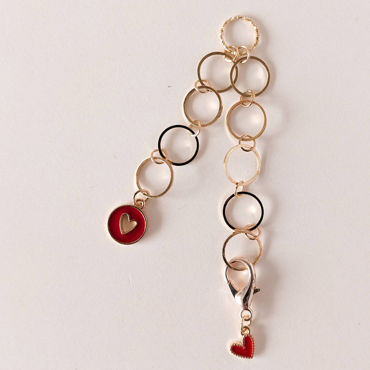 Gold chain row counter with heart charms on a light gray background