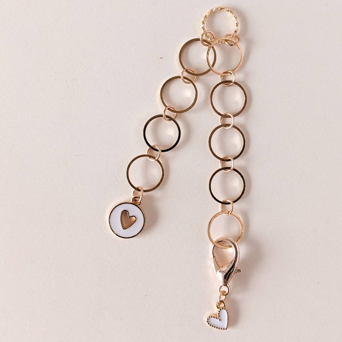 Gold row counter chain with white heart charms on a light beige background