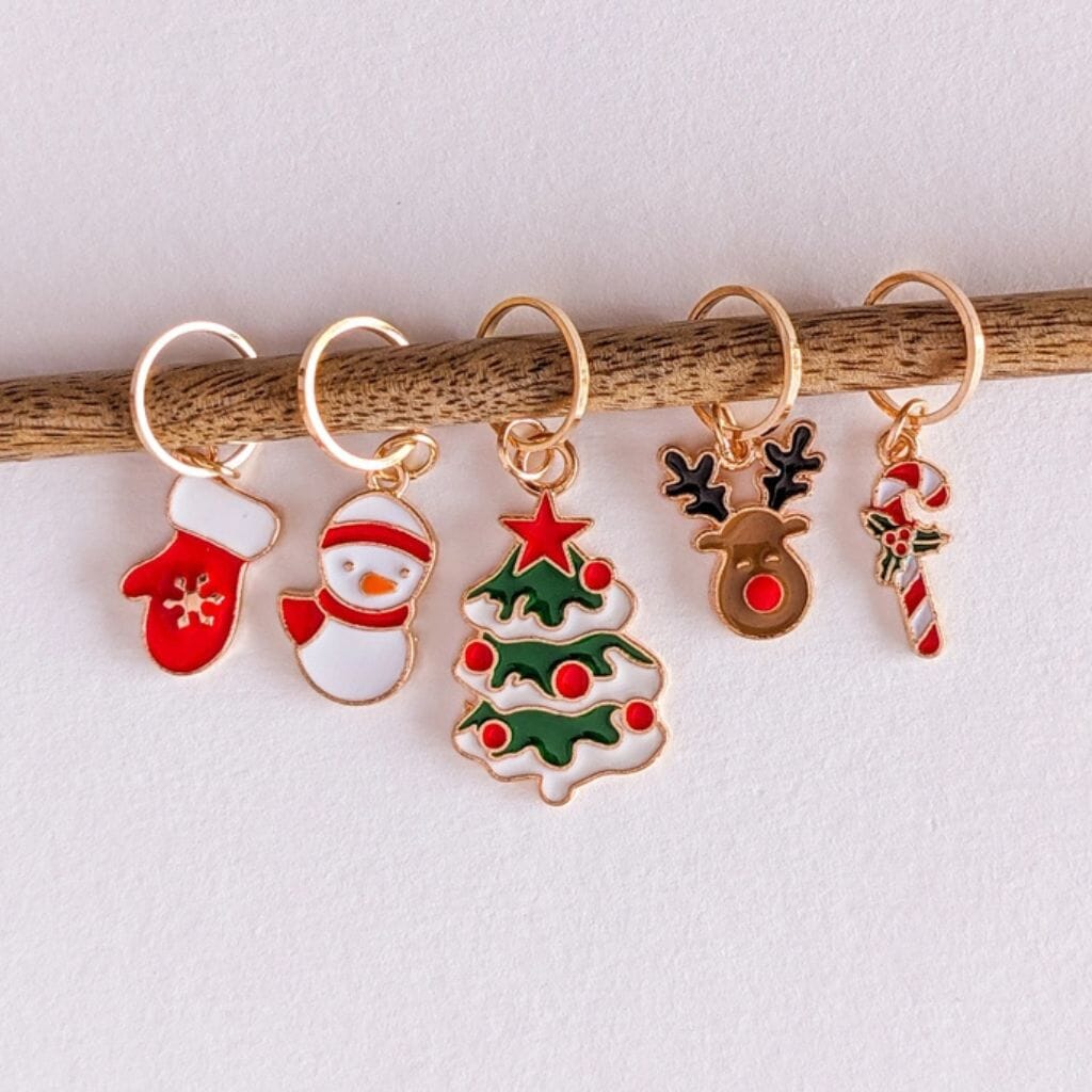 Set of Christmas-themed stitch markers on a stick against a white background