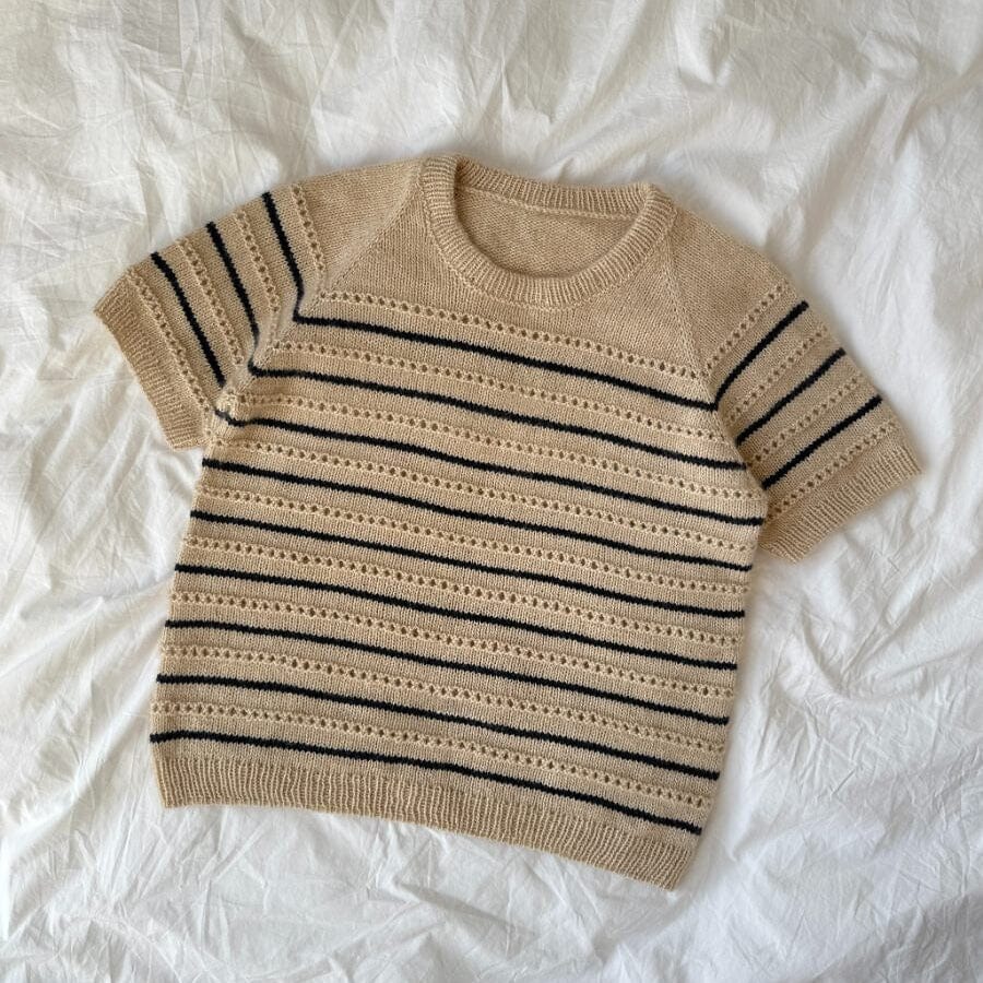 Beige and black striped sweater on a white fabric background