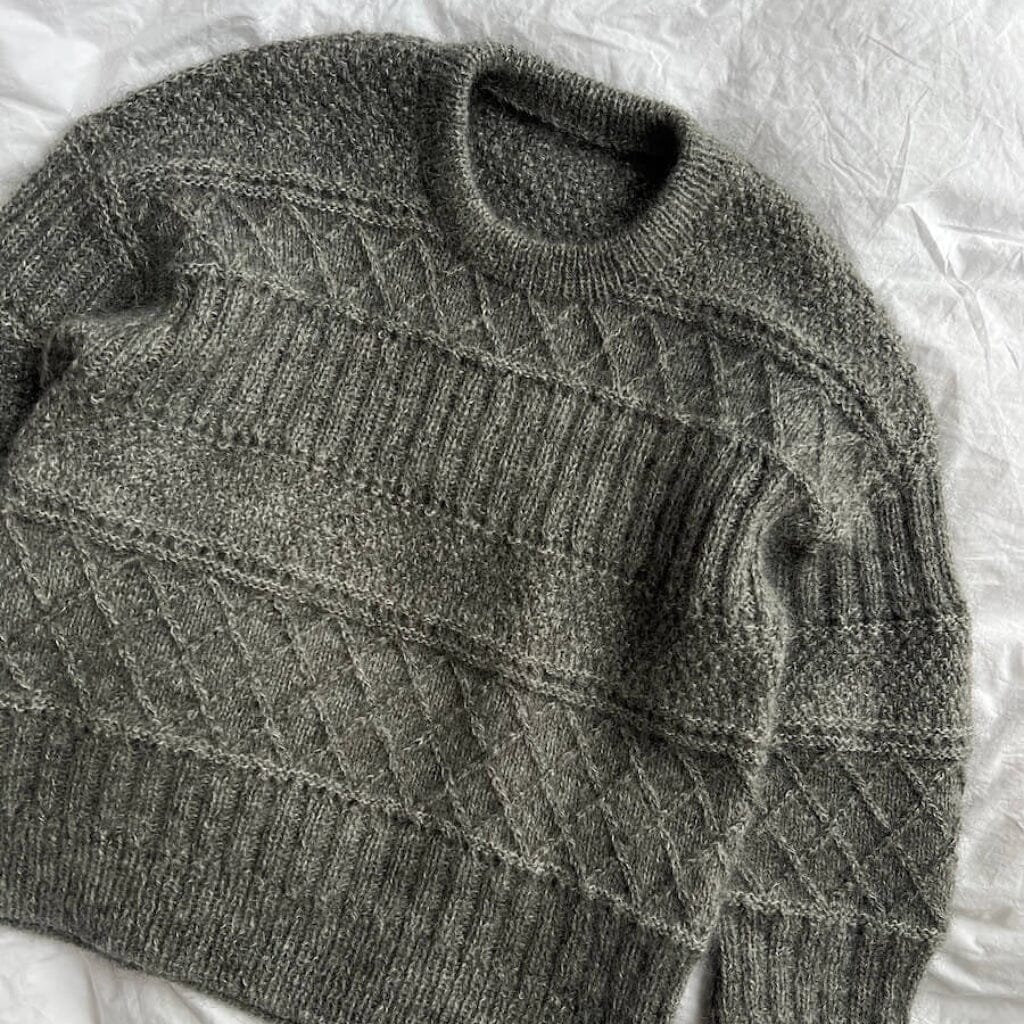 Gray knitted sweater on a white textured surface
