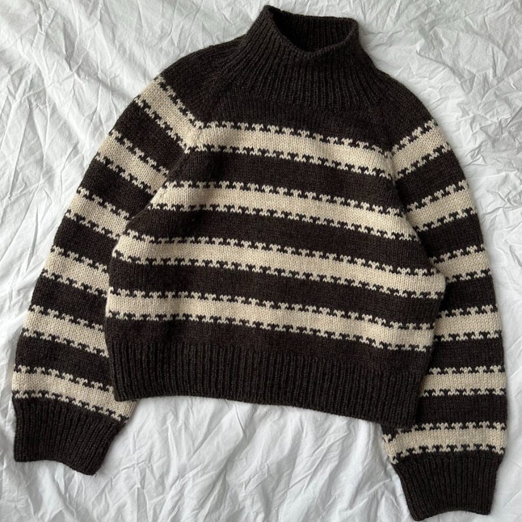 Black and beige striped sweater on a textured white background
