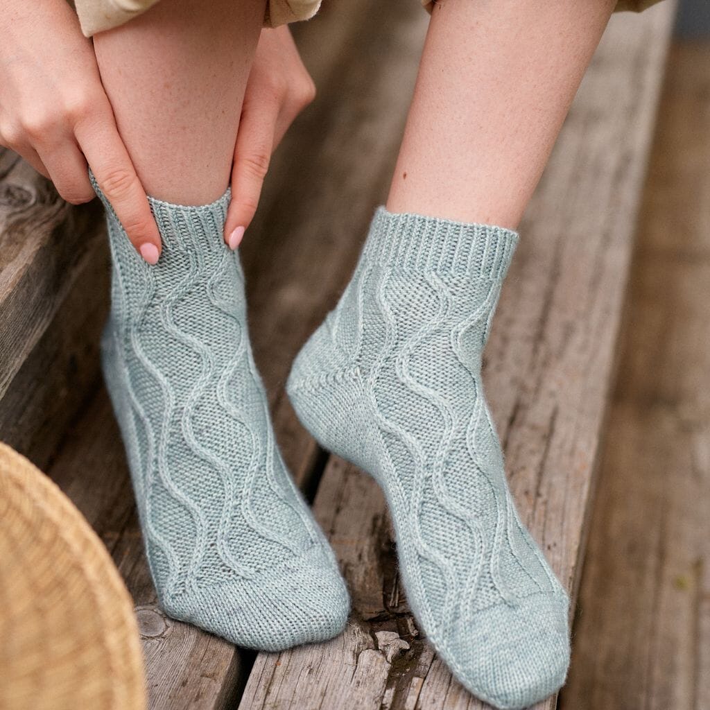 Light blue knitted socks on a wooden surface