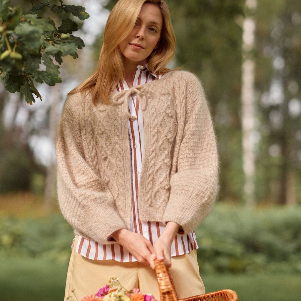 Woman wearing a beige knitted cardigan in a natural setting
