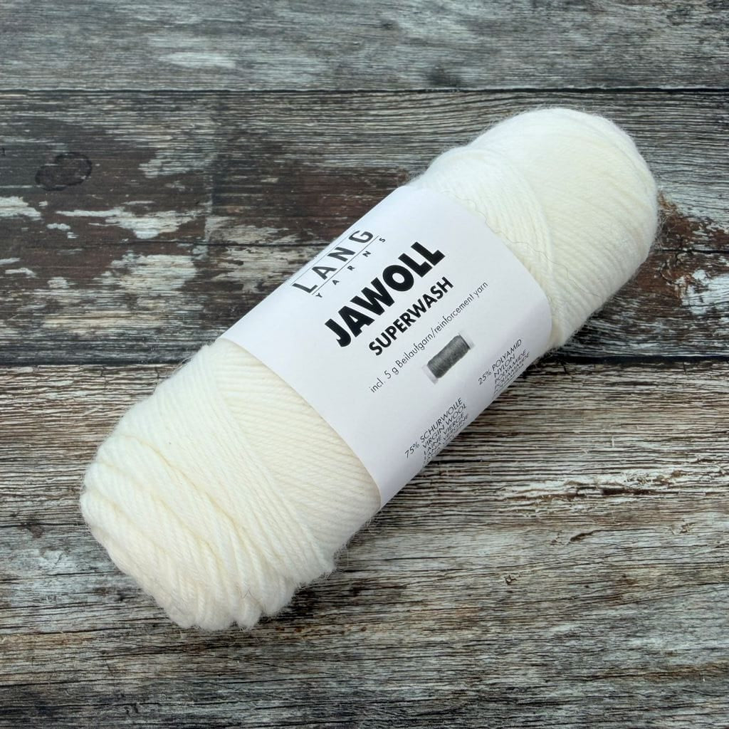 Bundles of Lang Yarns Jawoll Superwash yarn in various colors on a wooden surface.