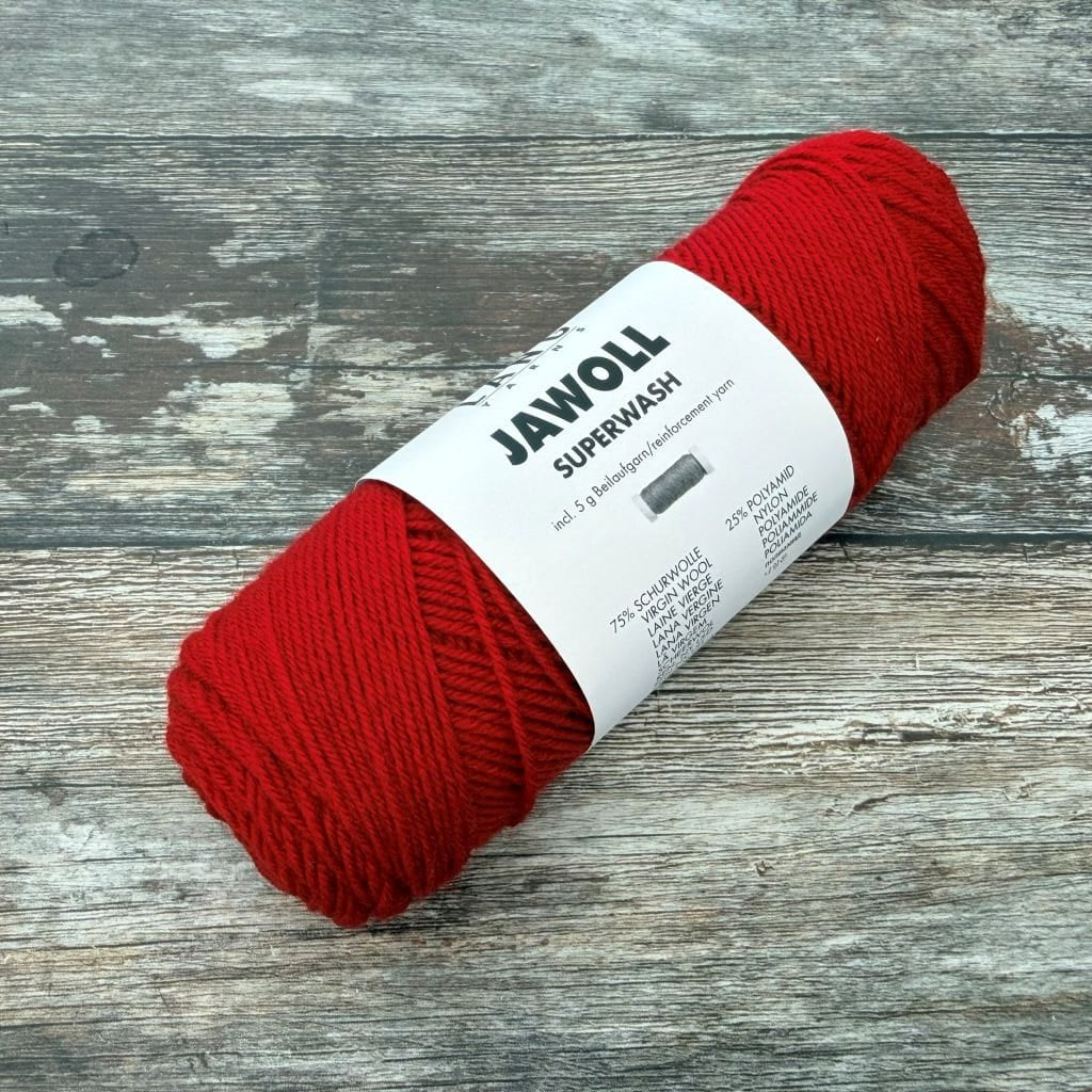 Red ball of yarn with a label on a wooden surface