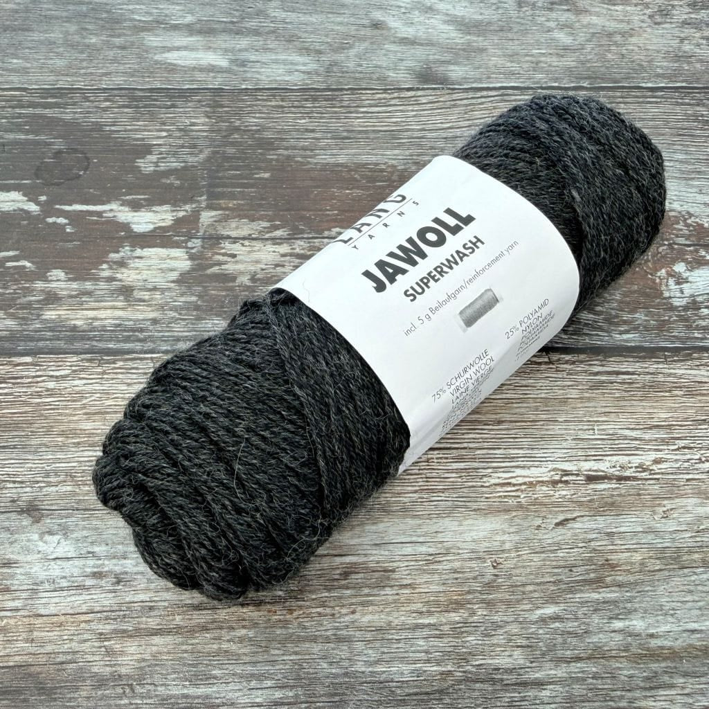 Charcoal ball of yarn with a label on a wooden surface