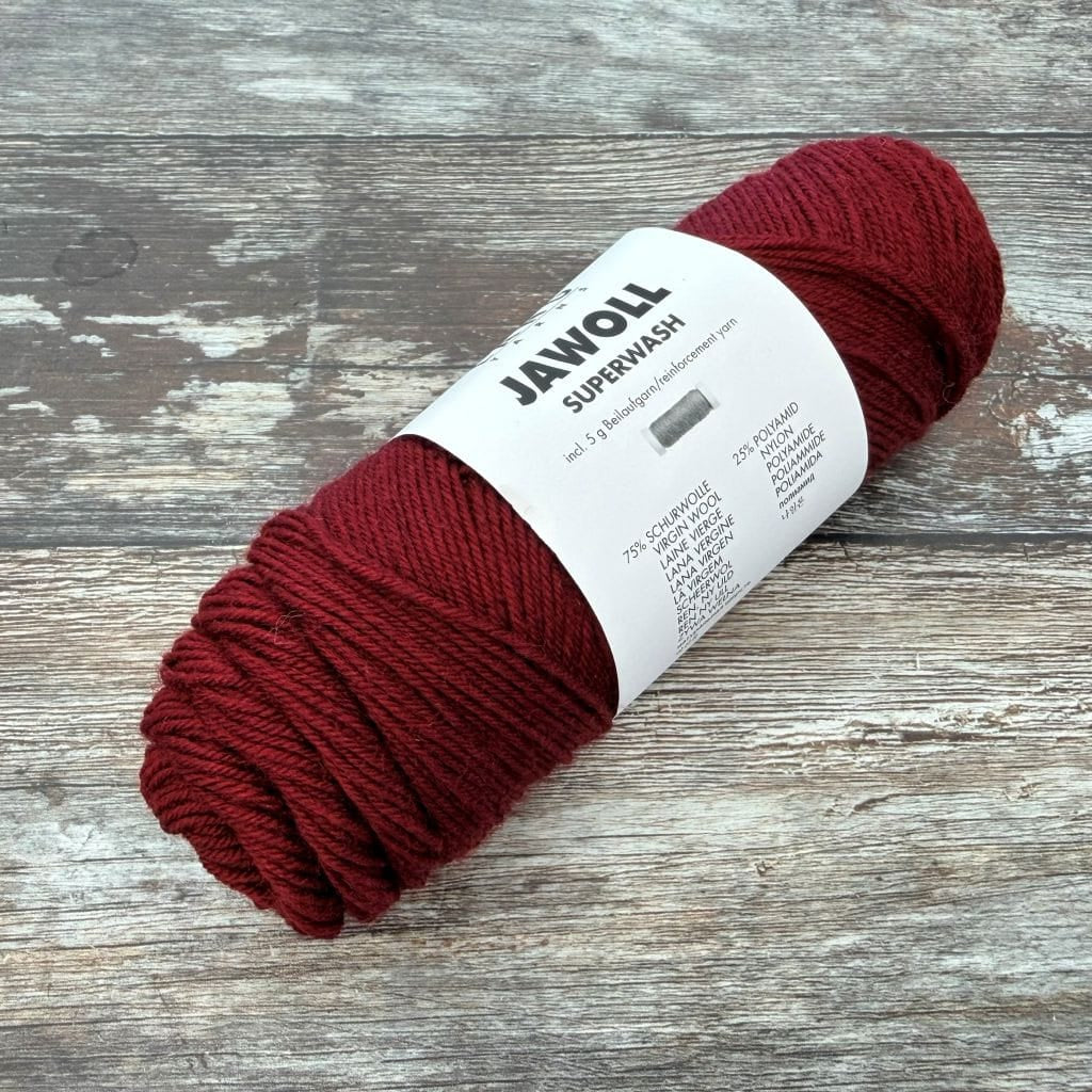 burgundy  ball of yarn with a label on a wooden surface