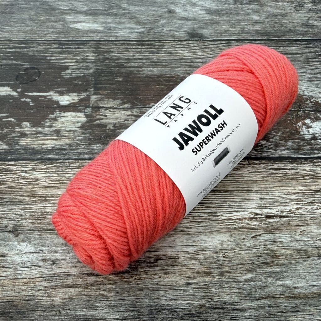 Ball of pink yarn with a label on a wooden surface