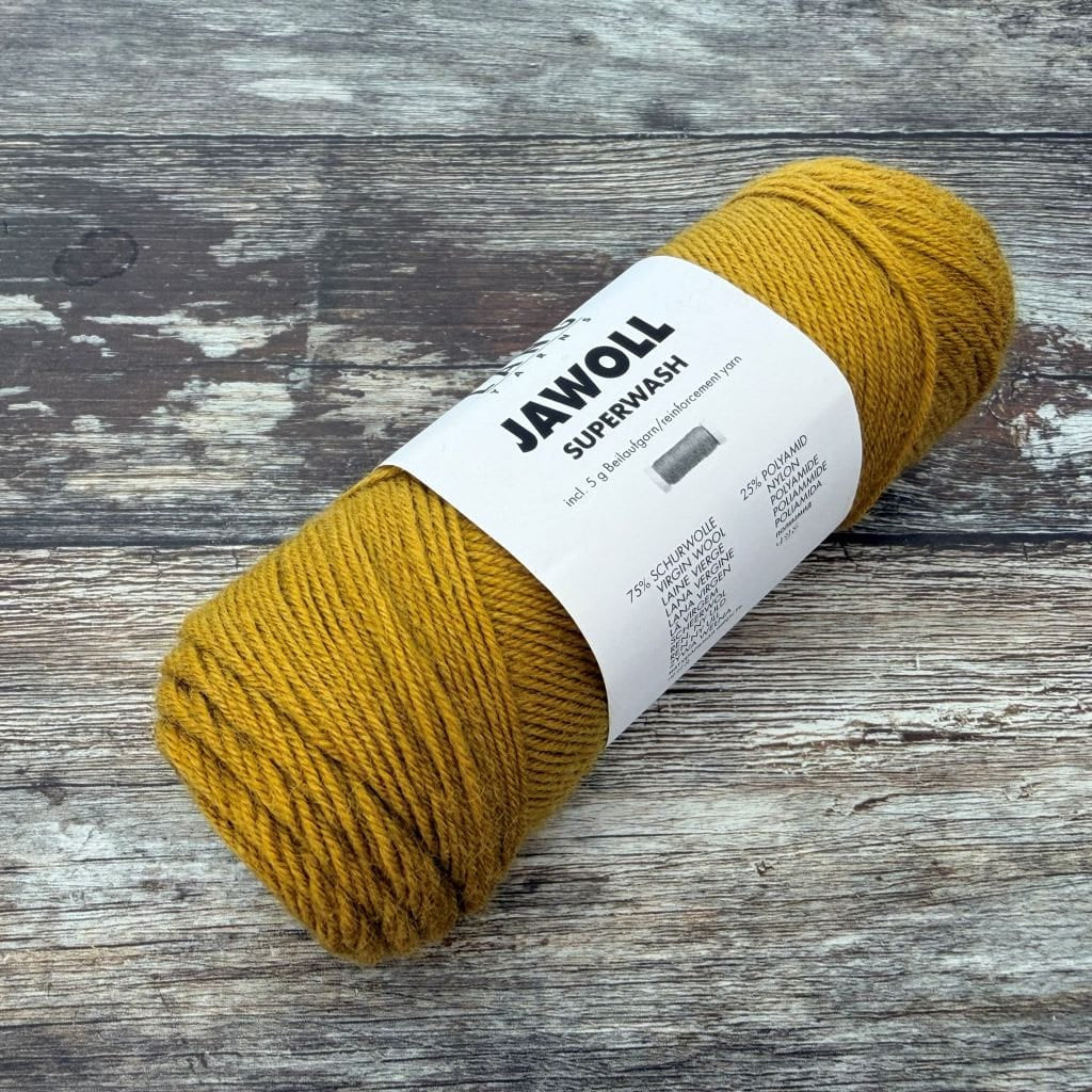 Mustard yellow ball  of yarn with a label on a wooden surface