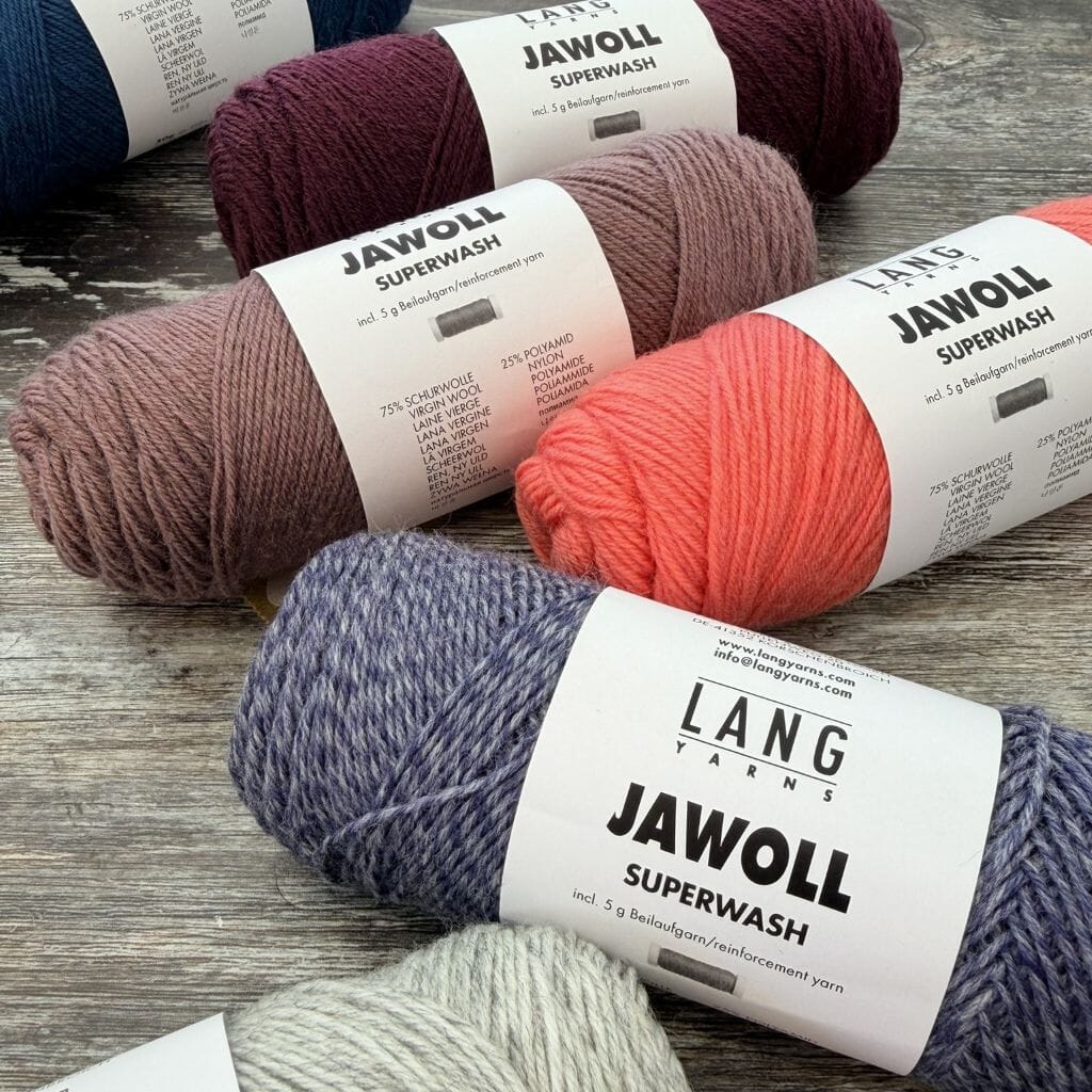 Bundles of Lang Yarns Jawoll Superwash yarn in various colors on a wooden surface.