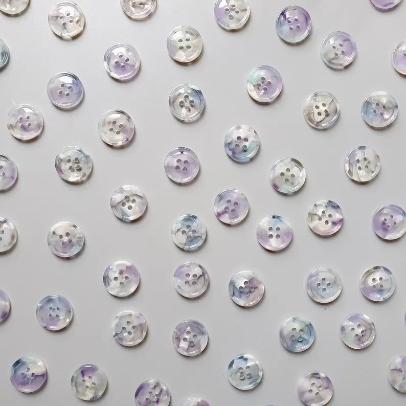 Pattern of round buttons with a metallic sheen on a light gray background