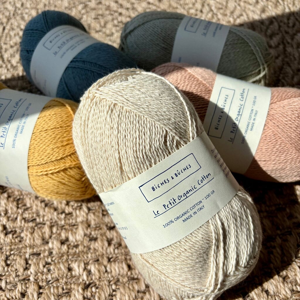 5 balls of cotton on woven surface, with label 'le petit organic cotton'