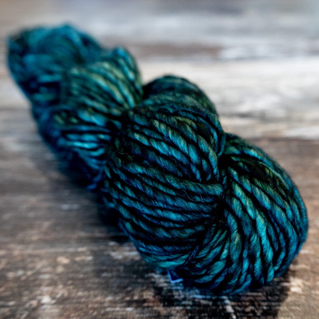 Blue and green skein of yarn on a wooden surface