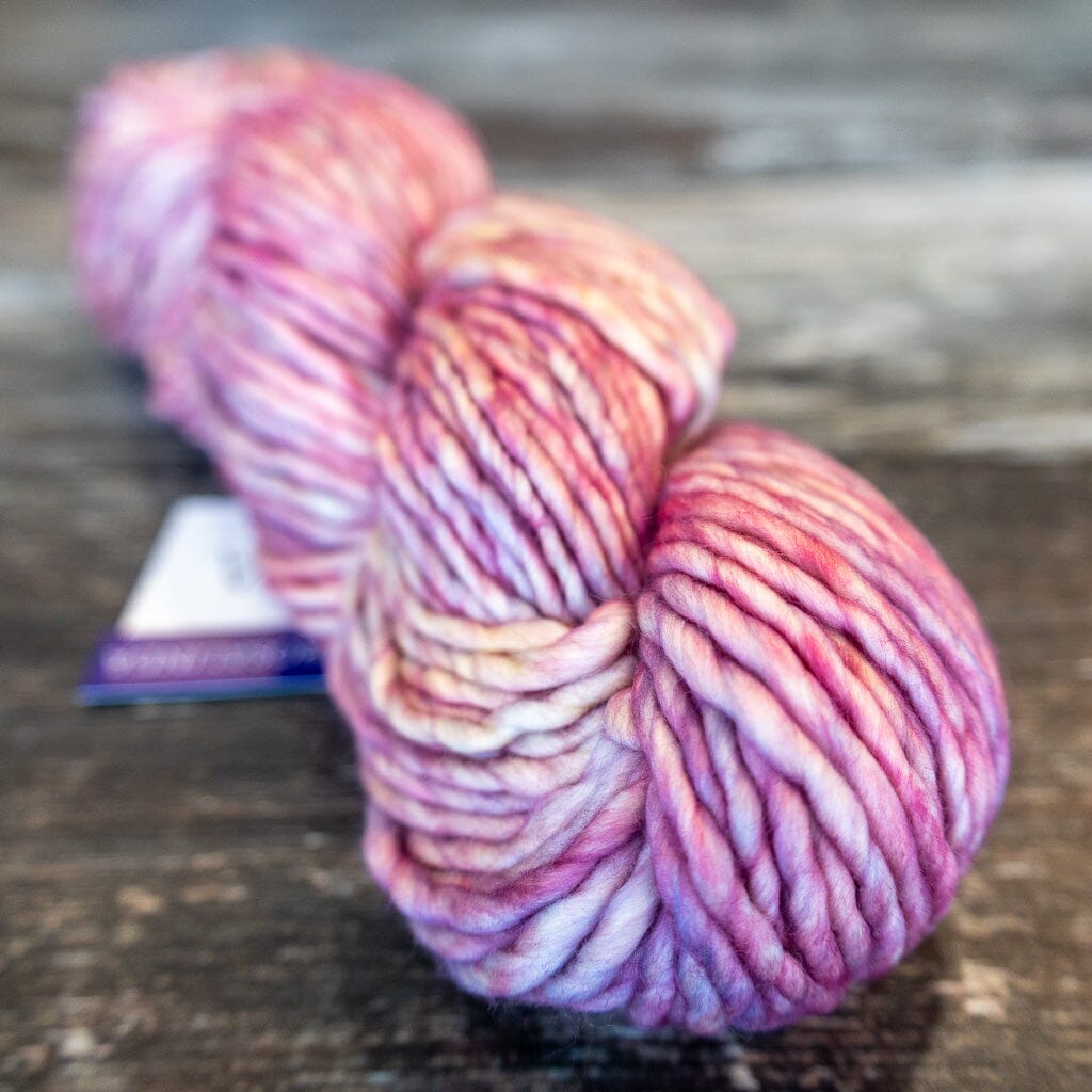 Multicoloured skein of yarn in pinks on a wooden surface