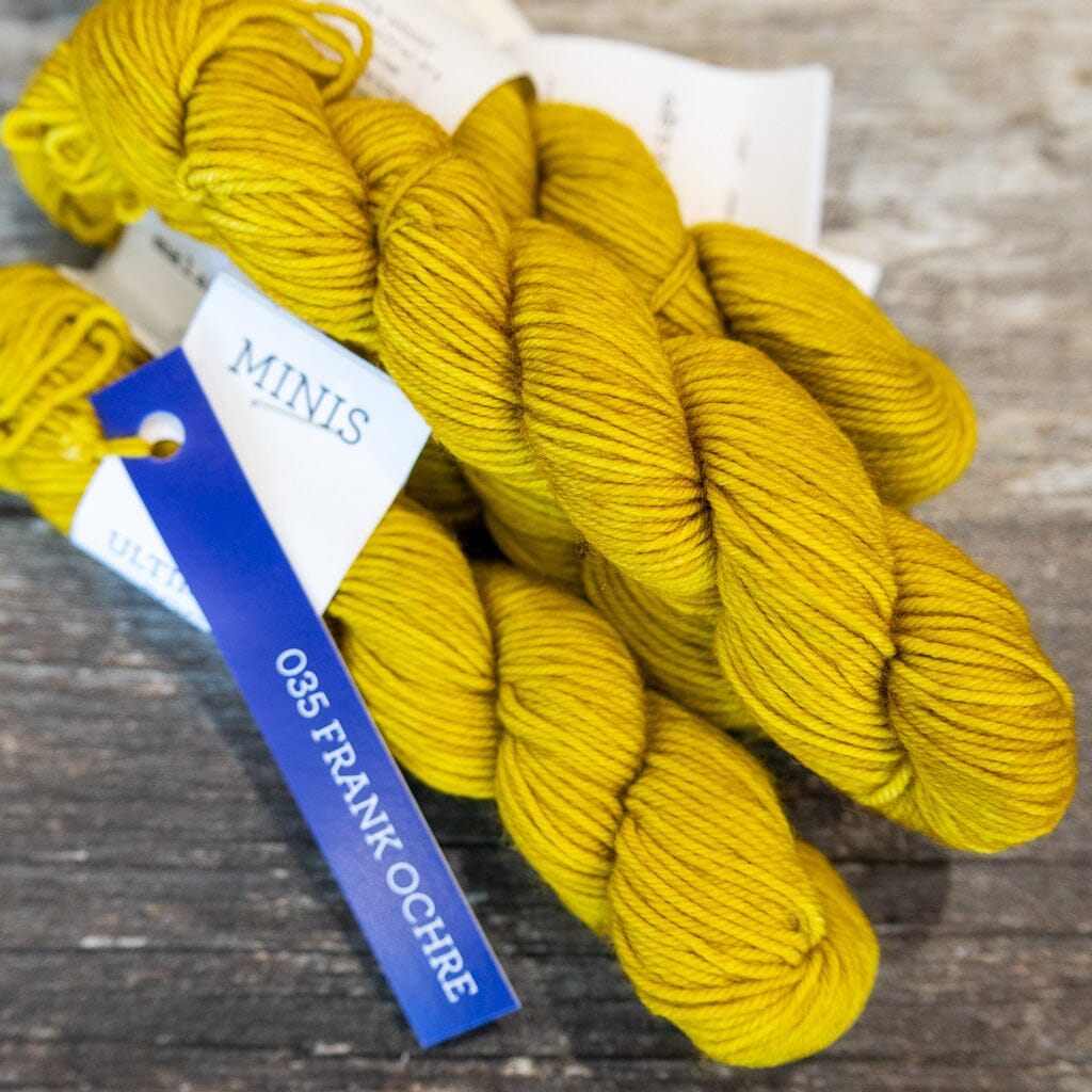 Three skeins of yellow yarn with a label on a wooden surface