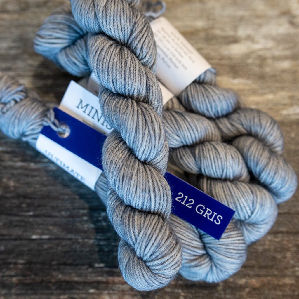 Gray yarn skein with a label on a wooden surface